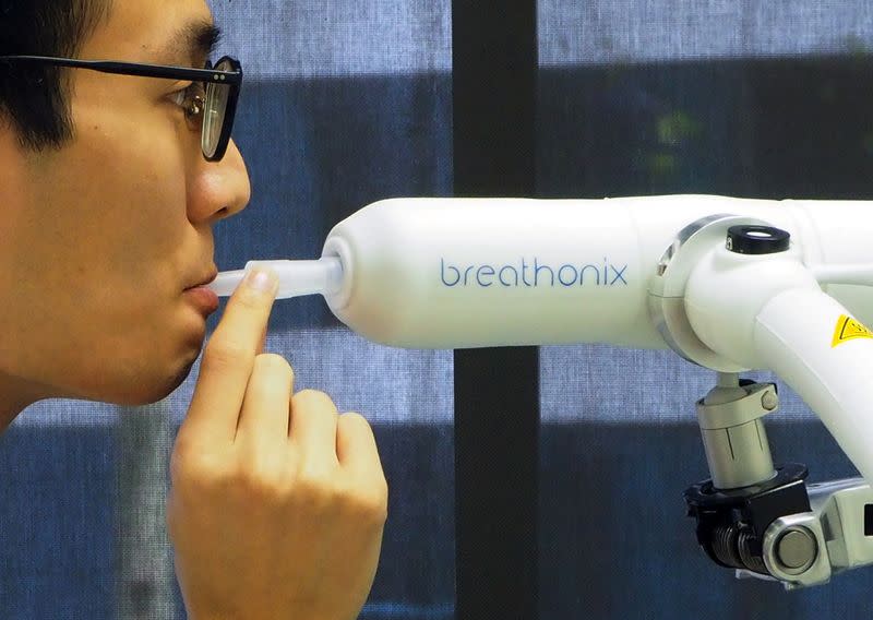 A staff member demonstrates the usage of Breathonix breathalyzer test kit in Singapore