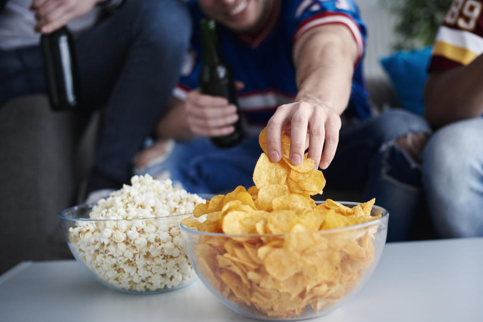 Close up of mens hand grabbing crisps. (Getty Images)