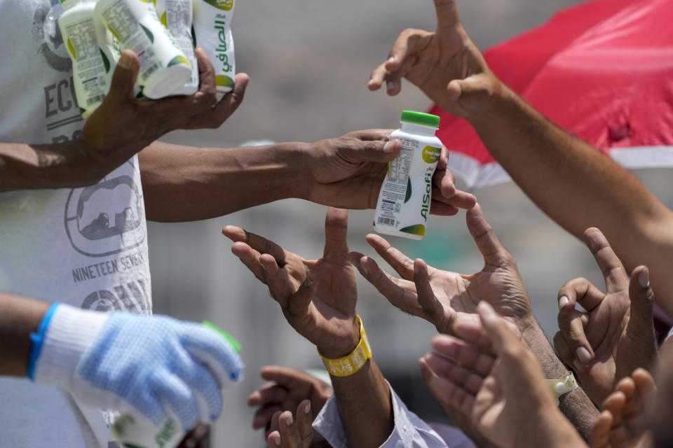 Pilgrims receive free cold drinks after they cast stones at a pillar in the symbolic stoning of the devil, the last rite of the annual Hajj pilgrimage, in Mina near the holly city of Mecca, Saudi Arabia, Thursday, June 29, 2023. (AP Photo/Amr Nabil)