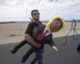 President Donald Trump supporter Mick White, of Fullerton, carries a Trump effigy he found face down in the sand after a march turned violent in Huntington Beach, Calif., on Saturday, March 25, 2017. (Mindy Schauer/The Orange County Register via AP)