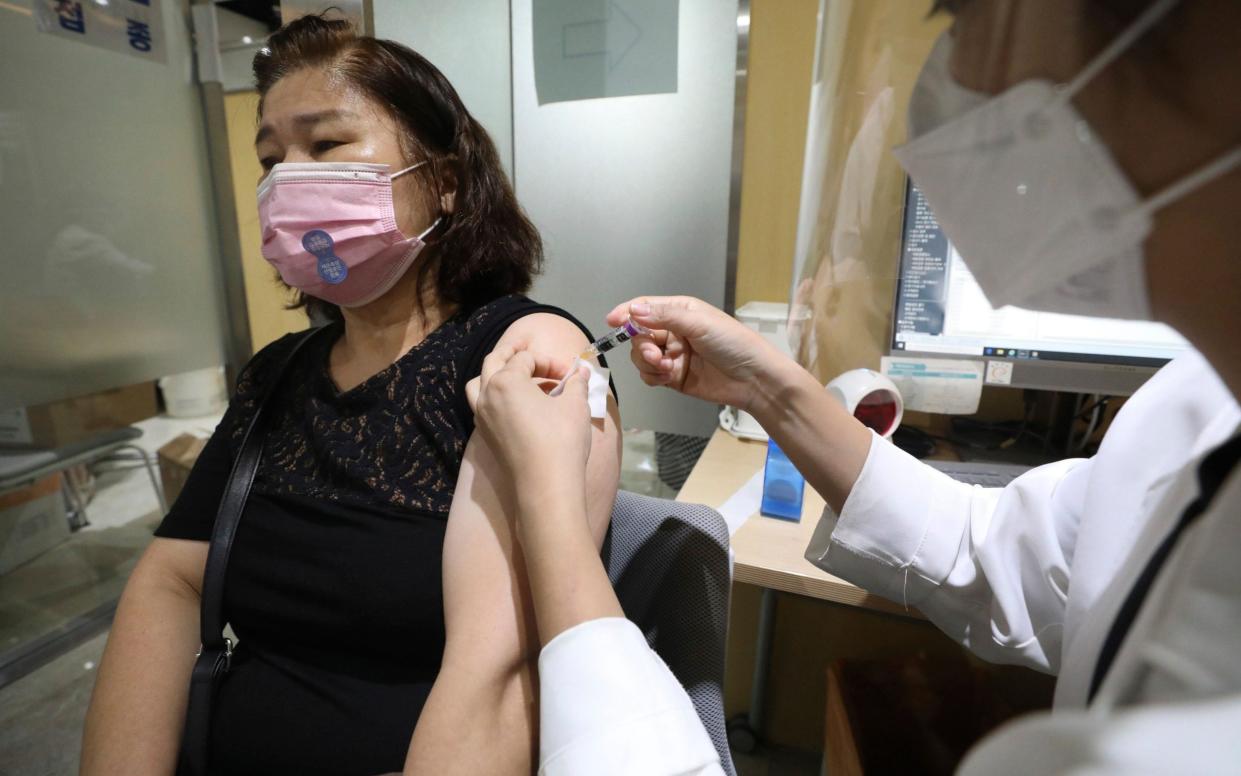 A woman wearing a face mask is given a flu shot at the Korea Association of Health Promotion in Seoul - Newsis