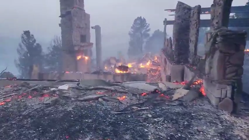 In the glow of fire and the light of day, damage done to a structure in Ruidoso during the McBride Fire can be seen.