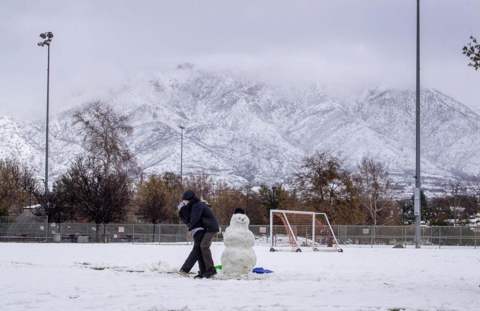 a snowman amidst the rare sight of falling snow in Southern California at Yucaipa Community Park in Yucaipa