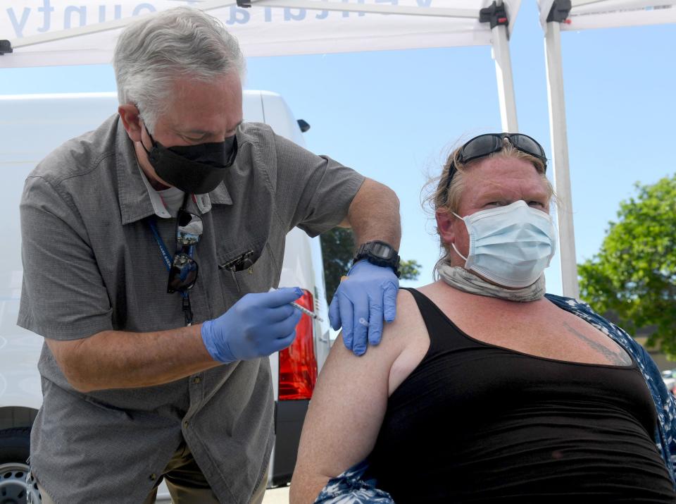 Paramedic David Liske administers a COVID-19 booster shot to Michael Meade at the Island Pacific Seafood Market in Oxnard, Calif., on Sept. 23.