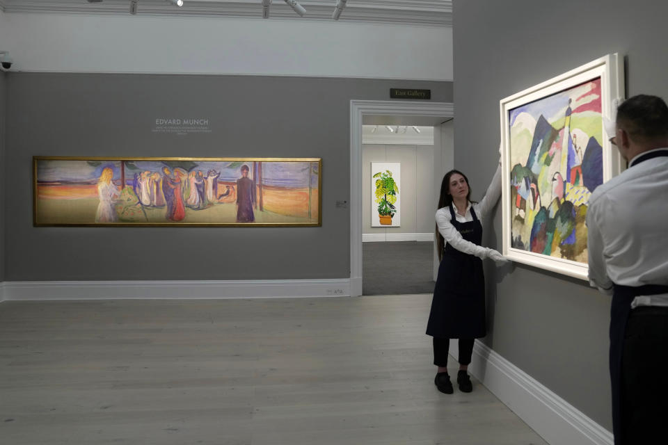 Members of staff hold the four-metre-long painting, left, " Dance on the Beach " by Norwegian painter Edvard Munch, on display during a media preview of Sotheby's auction, in London, Wednesday, Feb. 22, 2023. The piece has an estimated price of 12-20 million pounds and will go on auction on March 1, 2023. (AP Photo/Kin Cheung)