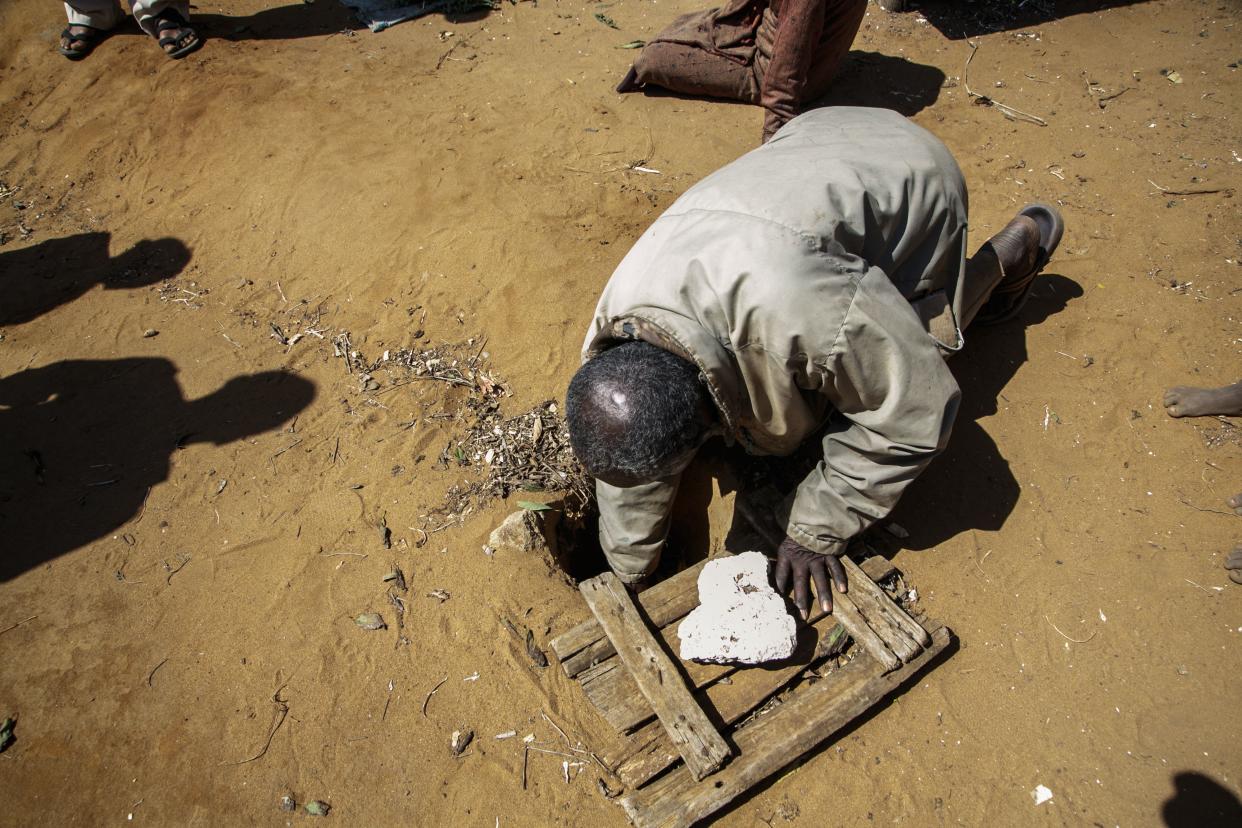 Jonarson Revoria, a farmer in the village of Ankilidoga, reaches into a small basin dug in the ground to collect rainwater.