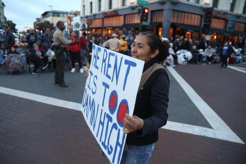 Pasadena, CA - January 01: A protestor holds up a "RENT IS TOO DAMN HIGH" sign before the Rose Parade on Monday, Jan. 1, 2024 in Pasadena, CA. (Michael Blackshire / Los Angeles Times)