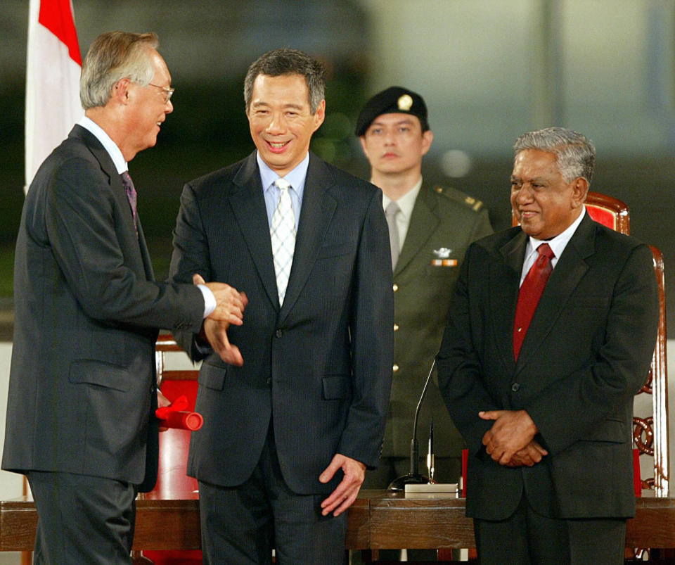SINGAPORE, SINGAPORE:  Former prime minister Goh Chok Tong (L) shakes the hands with newly installed Prime Minister Lee Hsien Loong (C) as President S.R. Nathan (R) looks on after the oath taking ceremony at the Istana presidential palace in Singapore, 12 August 2004. Lee succeeded Goh Chok Tong, 63, who was in power for 14 years and has now taken the title senior minister as Lee&#39;s closest adviser. AFP PHOTO/ROSLAN RAHMAN  (Photo credit should read ROSLAN RAHMAN/AFP via Getty Images)