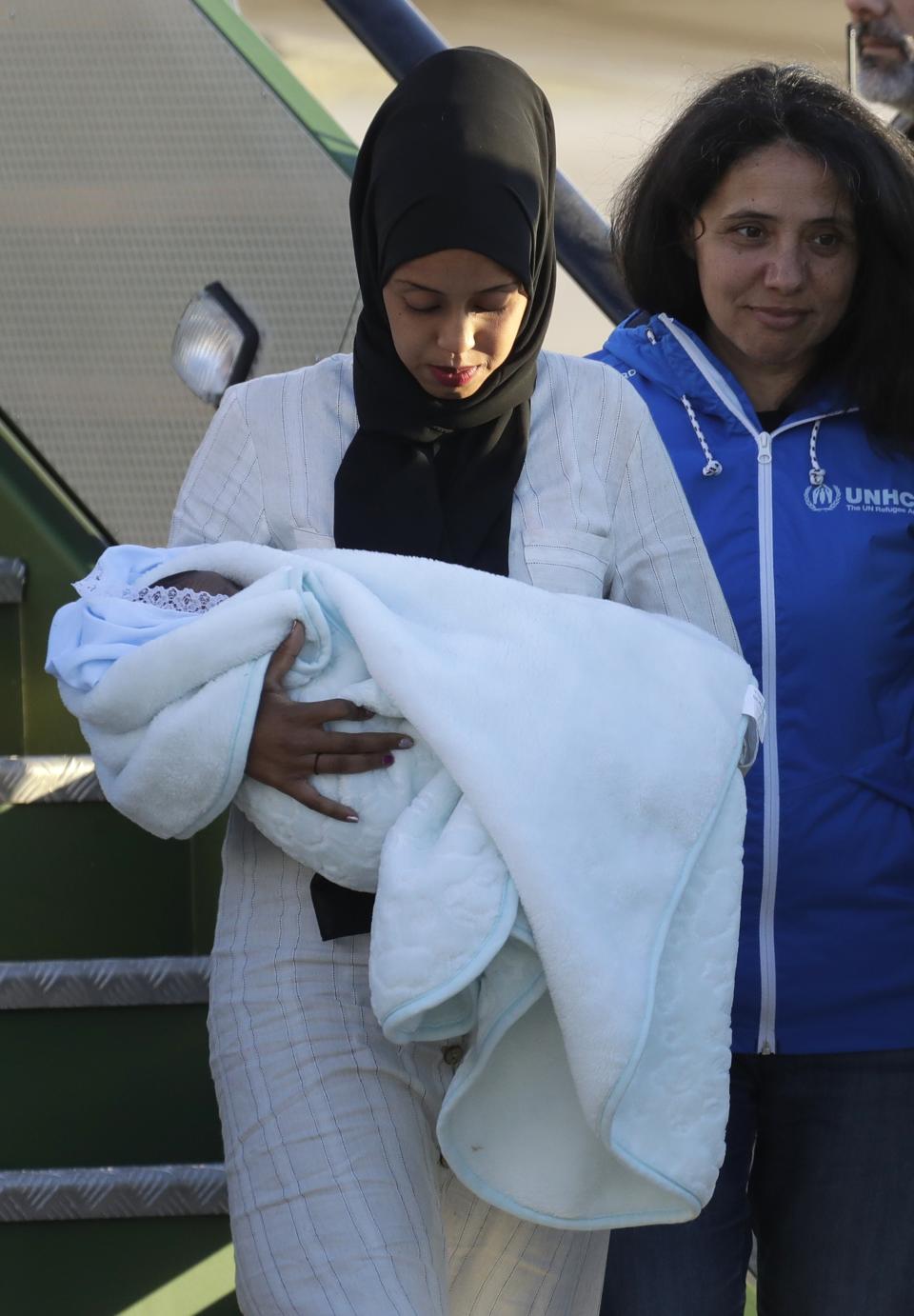 A woman holding a baby disembarks from an Italian military aircraft arriving from Misrata, Libya, at Pratica di Mare military airport, near Rome, Monday, April 29, 2019. Italy organized a humanitarian evacuation airlift for a group of 147 asylum seekers from Ethiopia, Eritrea, Somalia, Sudan and Syria. (AP Photo/Andrew Medichini)