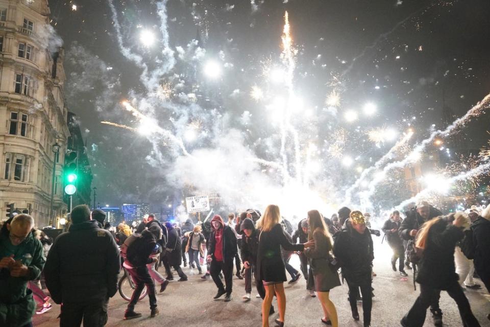 Fireworks are let off as people take part in the Million Mask March 2021 in Parliament Square (PA)