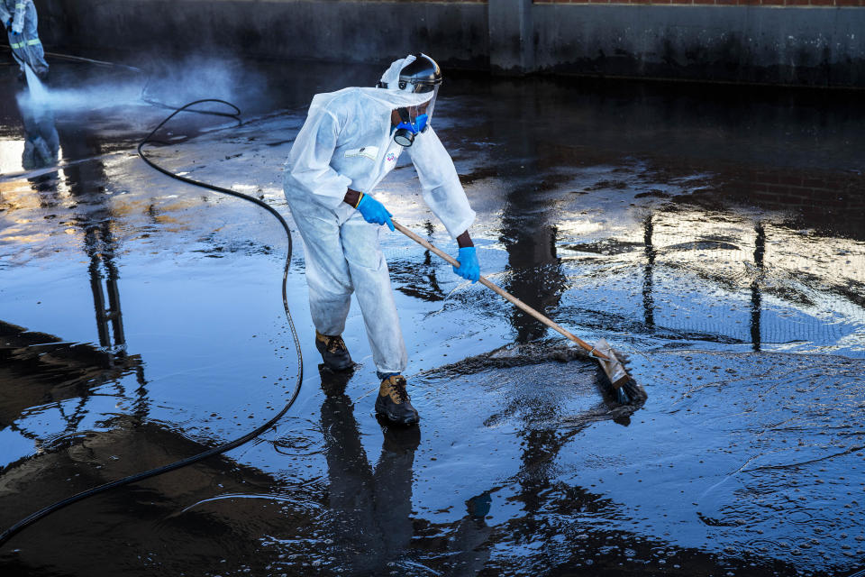 FILE — In this May 20, 2020, file photo workers sanitize a mini-bus taxi rank in Alexandra township, Johannesburg. South Africa’s reported coronavirus are surging. Its hospitals are now bracing for an onslaught of patients, setting up temporary wards and hoping advances in treatment will help the country’s health facilities from becoming overwhelmed. (AP Photo/Jerome Delay, File)