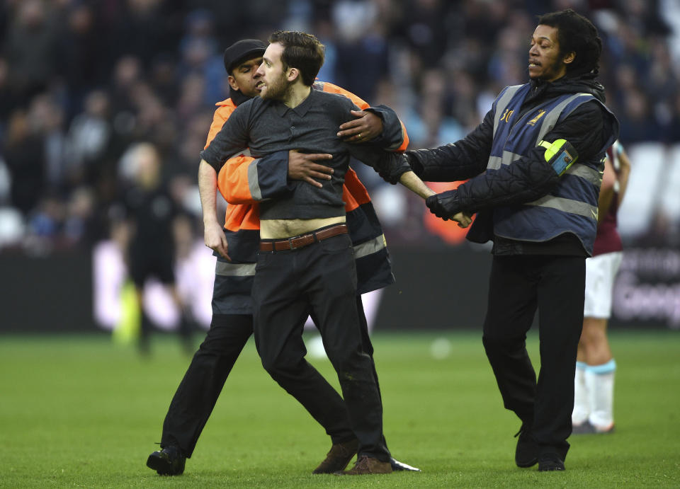 A Pitch invader is seized by security staff during the English Premier League soccer match between Burnley and West Ham at the Olympic London Stadium in London, Saturday, March 10, 2018. (Daniel Hambury/PA via AP)