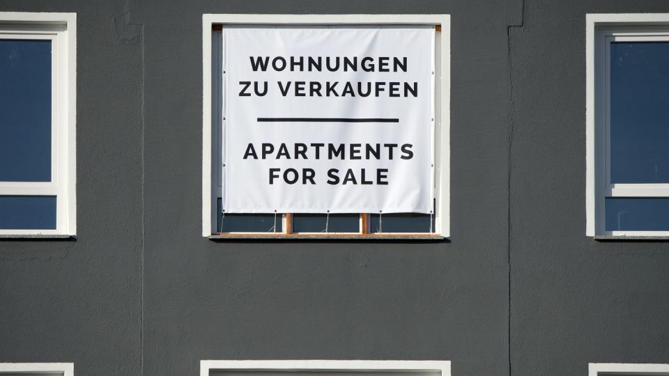 Mit einem großen Plakat werden Wohnungen zum Kauf angeboten. Weniger Maklerkosten entlasten Immobilienkäufer vor allem in Städten, wo Häuser und Wohnungen sehr teuer sind.