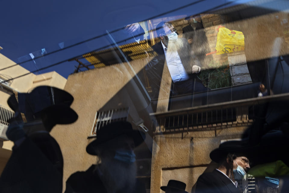 Ultra-Orthodox Jews, followers of the Hasidic sect of Shomrei Emunim, wearing protective face masks amid concerns over the country's coronavirus outbreak, gather for the funeral of their Rabbi Refael Aharon Roth, 72, who died from the coronavirus, in Bnei Brak, Israel, Aug. 13, 2020. (AP Photo/Oded Balilty)