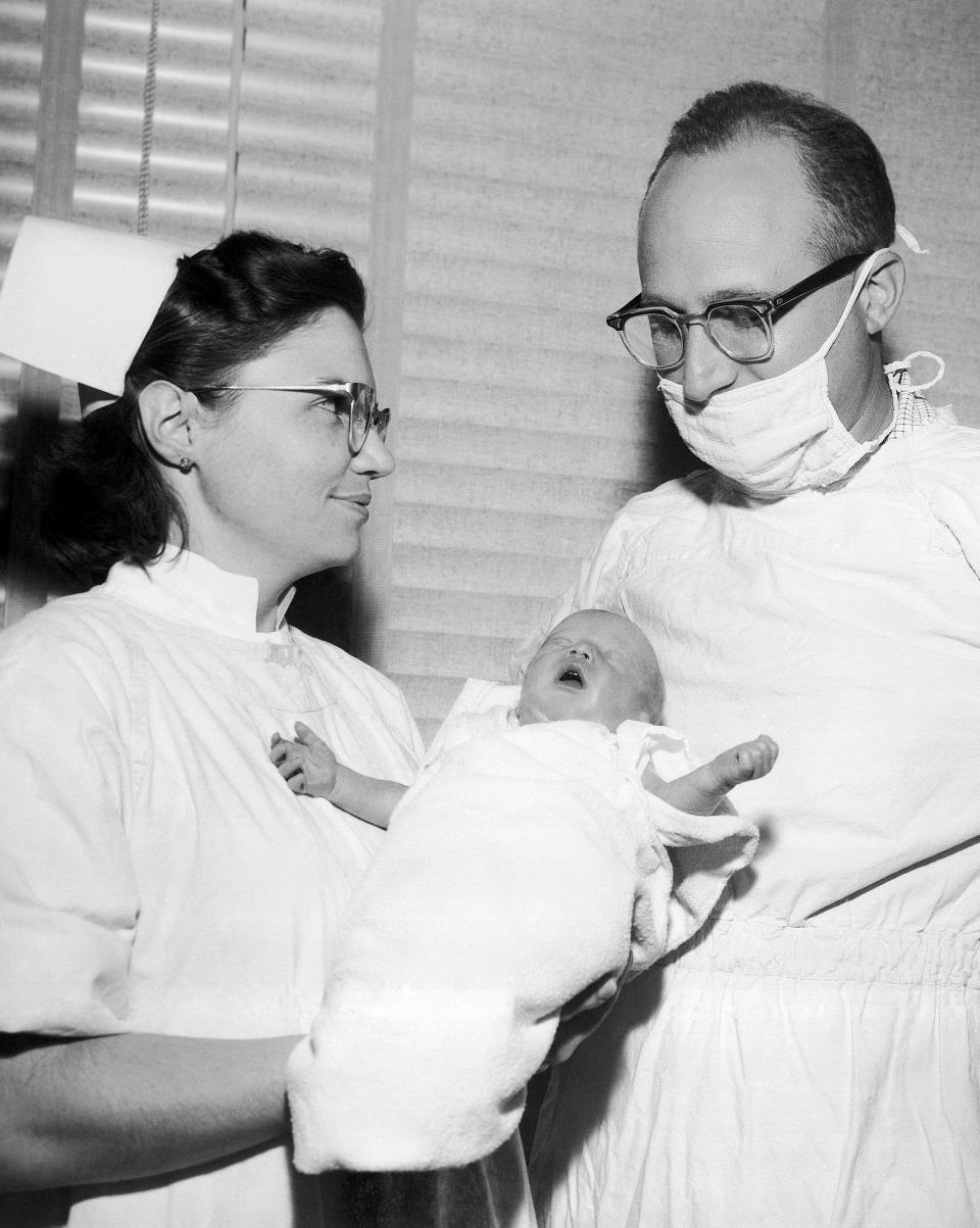 A doctor and nurse holding a baby.