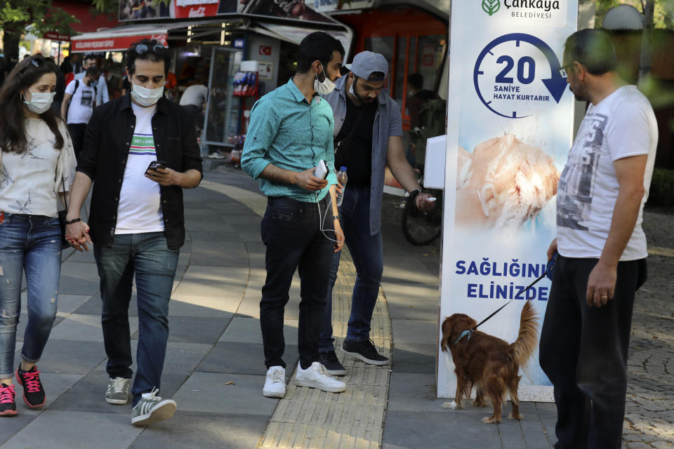 People wearing face masks to protect against the new coronavirus, use disinfectant at the entrance of a public garden, in Ankara, Turkey, Sunday, June 14, 2020. Turkey's President Recep Tayyip Erdogan has revealed Tuesday new plans to ease restrictions in place to curb the spread of the coronavirus, including the July 1 reopening of theaters, cinemas and other entertainment centers.(AP Photo/Burhan Ozbilici)