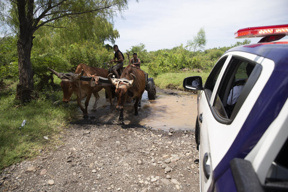 Men driving an ox cart pass agents from the new border patrol, near La Paz River on the border with Guatemala, in La Hachadura, El Salvador, Thursday, Sept. 12, 2019. The deployment of a new border patrol is part of an agreement between the Salvadoran government and acting U.S. Homeland Security Secretary Kevin McAleenan to slow the flow of migrants trying to reach the United States. (AP Photo/Moises Castillo)