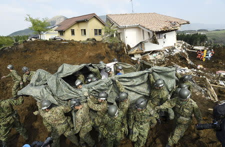 Japan Ground Self-Defense Force soldiers carry the a person found under landslide rubble following an earthquake in Minamiaso town, Kumamoto prefecture, southern Japan, in this photo taken by Kyodo April 19, 2016. Kyodo/via REUTERS