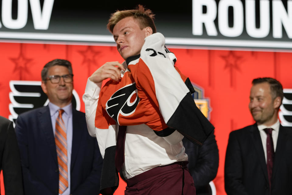 Matvei Michkov puts on a Philadelphia Flyers jersey after being picked by the team during the first round of the NHL hockey draft Wednesday, June 28, 2023, in Nashville, Tenn. (AP Photo/George Walker IV)