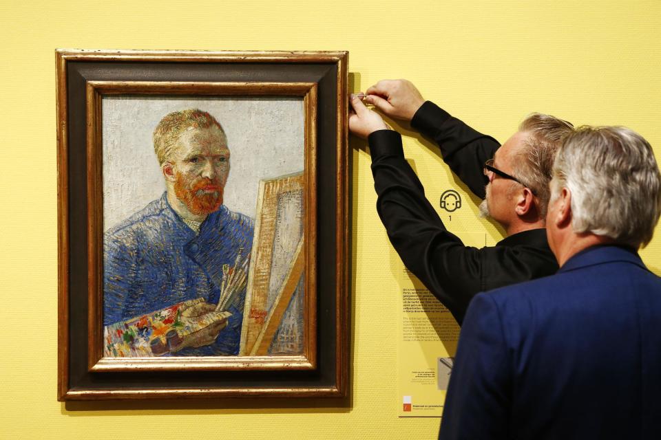 Curators hang an 1888 self-portrait of Vincent Van Gogh in which he painted himself behind a canvas, brushes and palette in hand, the final painting before the reopening after a seven-month renovation, kicking off with "Vincent At Work," an exhibition that shows Van Gogh's working methods, right down to the paints, brushes and other tools he used, Amsterdam, Netherlands, Wednesday, May 1, 2013. (AP Photo/Vincent Jannink)