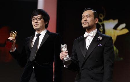 Diao Yinan (L) director of "Bai Ri Yan Huo" (Black Coal, Thin Ice) poses with his Golden Bear for Best Film next to actor Liao Fan (R) who poses with his Silver Bear for Best Actor, during the awards ceremony of the 64th Berlinale International Film Festival in Berlin February 15, 2014. REUTERS/Tobias Schwarz