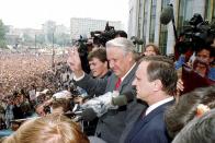 CORRECTS AGE FILE - Gennady Burbulis, right, stands next to Russian Republic President Boris Yeltsin, second right, making a V-sign to thousands of Muscovites at a rally in front of the Russian federation building to celebrate the failed military coup in Moscow, Aug. 22, 1991. Gennady Burbulis, who as a top aide to Russian President Boris Yeltsin helped prepare and signed the 1991 pact that led to the formal breakup of the Soviet Union, has died at age 76, Russian news reports said Sunday June 19, 2022. (AP Photo/Alexander Zemlianichenko, File)
