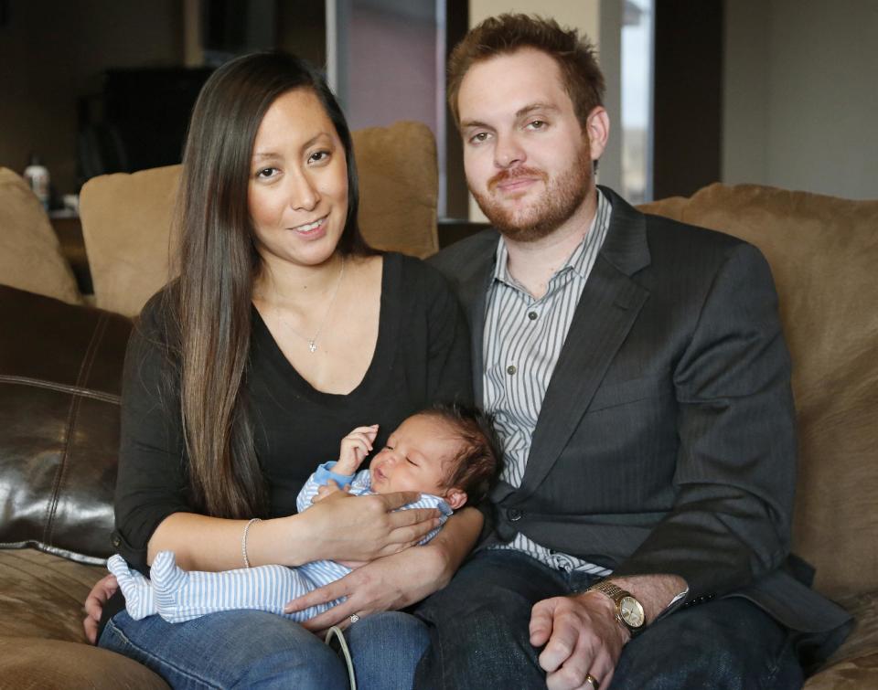 Jennifer Rogers, left, and her husband Nyle Rogers, right, smile as they hold their baby Jack Nicolas Rogers, in their home in Edmond, Okla., Tuesday, Jan. 14, 2014. Jack Nicolas Rogers was born Dec. 21, 2013. Jennifer Rogers is formerly Jennifer Doan, a Plaza Towers schoolteacher who was the subject of what became an iconic photograph of the Moore, Okla. tornado as firefighters are shown freeing a debris-covered Doan from the rubble of a collapsed wall. Doan was pregnant with Jack Nicolas at the time. Jack's middle name, Nicolas, is in memory of one of her students, who died in the tornado. (AP Photo/Sue Ogrocki)