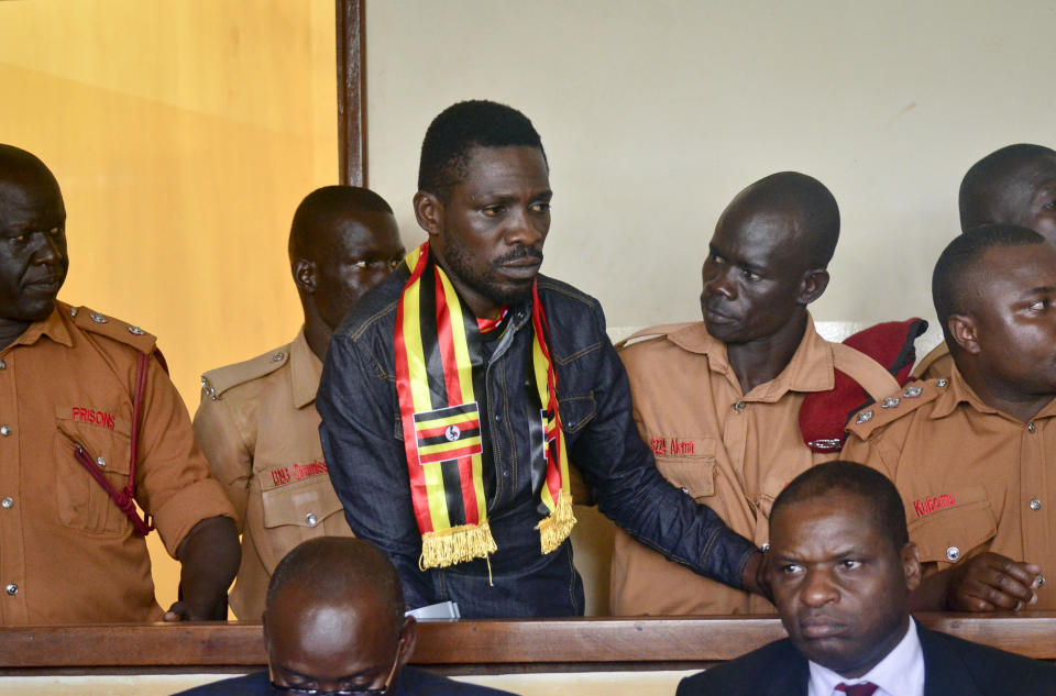 FILE - In this Thursday, Aug. 23, 2018 file photo, Ugandan pop star-turned-lawmaker Kyagulanyi Ssentamu, also known as Bobi Wine, center, arrives at a magistrate's court in Gulu, northern Uganda. Wine is due to return home on Thursday, Sept. 20, 2018 after seeking treatment in the United States for injuries suffered during alleged state torture. (AP Photo, File)