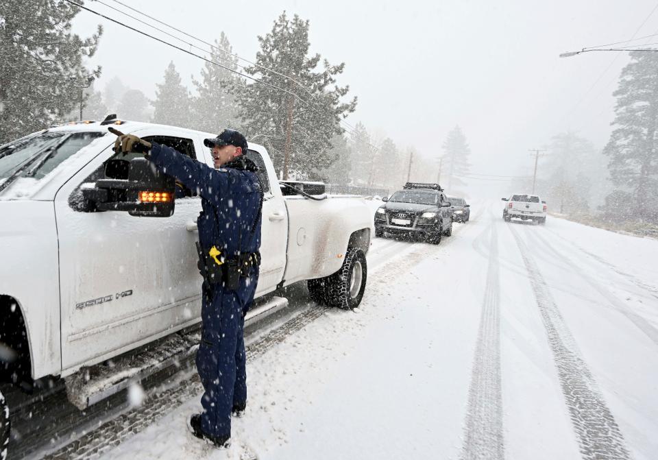 California Highway Patrol officer Mike Eshleman instructs a driver he may continue on Highway 2 in his 4-wheel drive vehicle as heavy snow falls near Wrightwood, California.