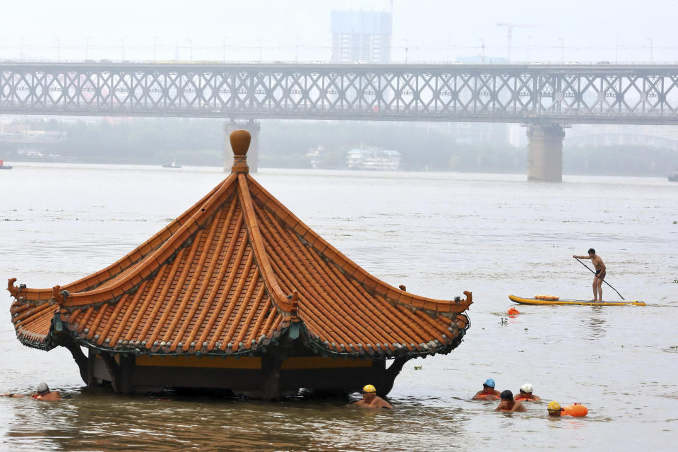 FILE - In this Wednesday, July 8, 2020 file photo, residents swim to a riverside pavilion submerged by the flooded Yangtze River in Wuhan in central China's Hubei province. An overheating world obliterated weather records in 2020 — an extreme year for hurricanes, wildfires, heat waves, floods, droughts and ice melt — the United Nations’ weather agency reported Wednesday, Dec. 2, 2020. (Chinatopix via AP)