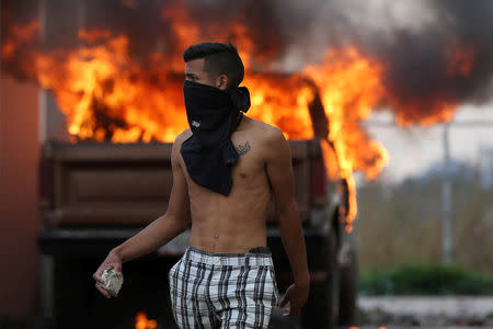A man hurls stones at the border between Venezuela and Brazil in Pacaraima, Brazil February 23, 2019. REUTERS/Bruno Kelly