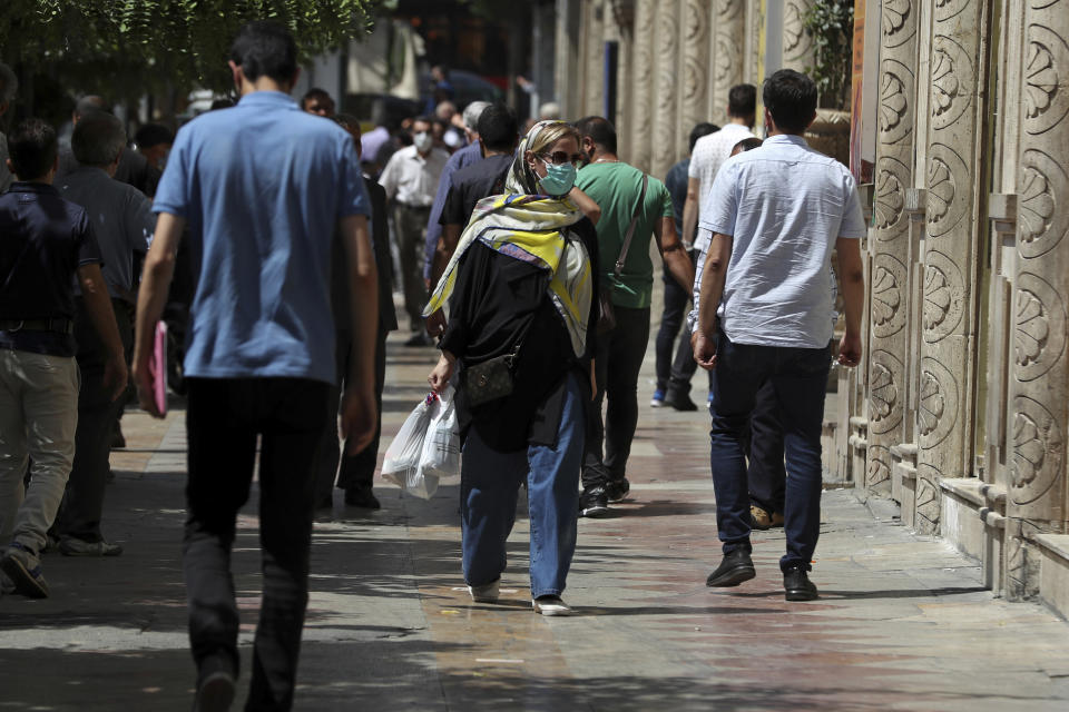 People walk on the sidewalk in Ferdowsi Street, Tehran, Iran, Sunday, June 12, 2022. Iran's currency Sunday dropped to its lowest value ever as talks to revive the country's tattered nuclear deal with world powers remained deadlocked. (AP Photo/Vahid Salemi)