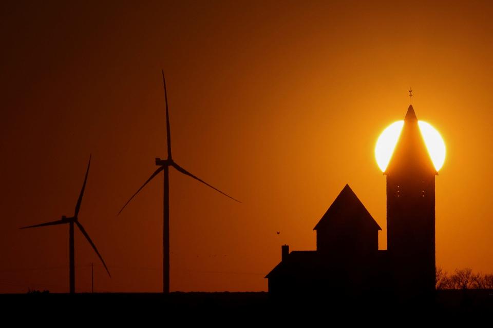 wind turbines and church silhouetted against sunset