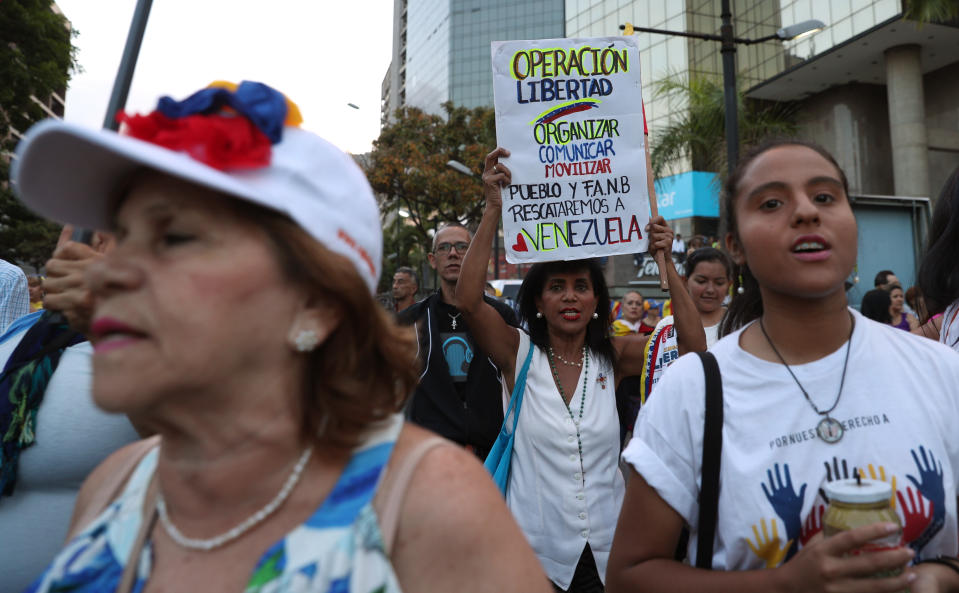 A woman holds a sign that reads in Spanish: "Operation Freedom. Organize. Communicate. Move. The people and the armed forces will rescue Venezuela." during a vigil for those killed in street fighting over the past week in Caracas, Venezuela, Sunday, May 5, 2019. Opposition leader Juan Guaidó called in vain for a military uprising to overthrow President Nicolas Maduro, and five people were killed in clashes between protesters and police. (AP Photo/Martin Mejia)