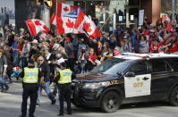 People march past police at a demonstration, part of a convoy-style protest participants are calling "Rolling Thunder," in Ottawa, Ontario, on Saturday, April 30, 2022. (Patrick Doyle/The Canadian Press via AP)