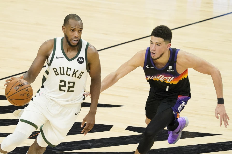 Milwaukee Bucks forward Khris Middleton (22) drives against Phoenix Suns guard Devin Booker during the second half of Game 5 of basketball's NBA Finals, Saturday, July 17, 2021, in Phoenix. (AP Photo/Matt York)