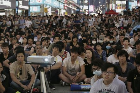 Pro-democracy protesters watch a live broadcast of a meeting between student leaders and government officials on a road blocked by them at Mongkok shopping district in Hong Kong October 21, 2014, REUTERS/Bobby Yip