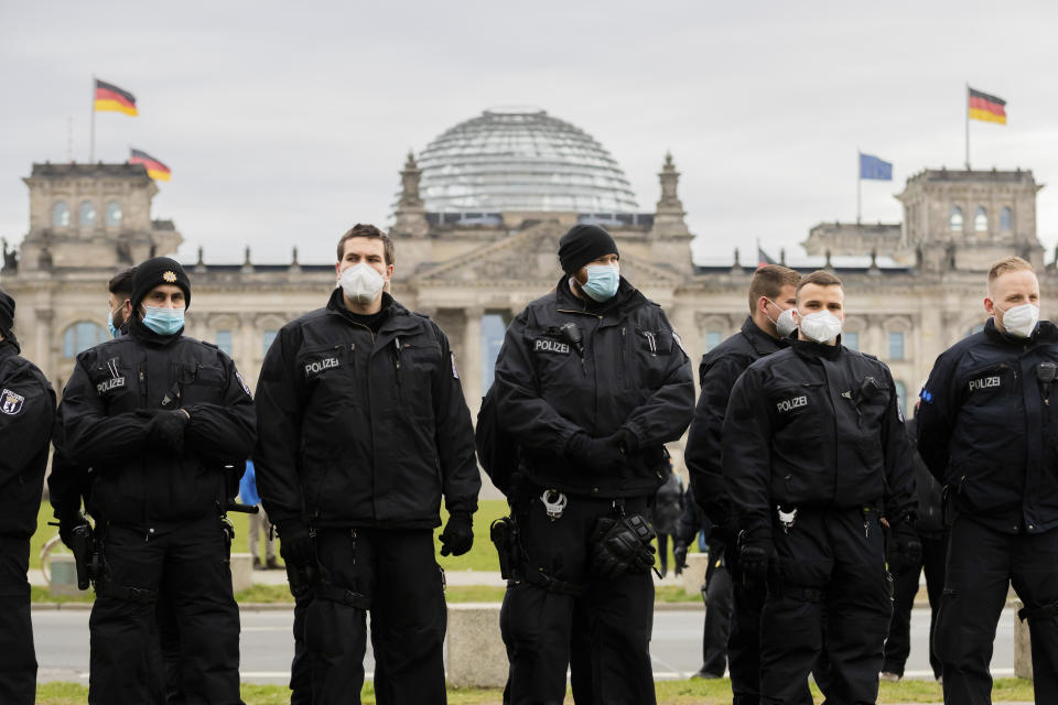 Police officers stand in front of the Reichstag building during a rally against the Corona measures as lawmakers discuss a federal new controversial law to fight the pandemic in Berlin, Germany, Friday, April 16, 2021. (Christoph Soeder/dpa via AP)