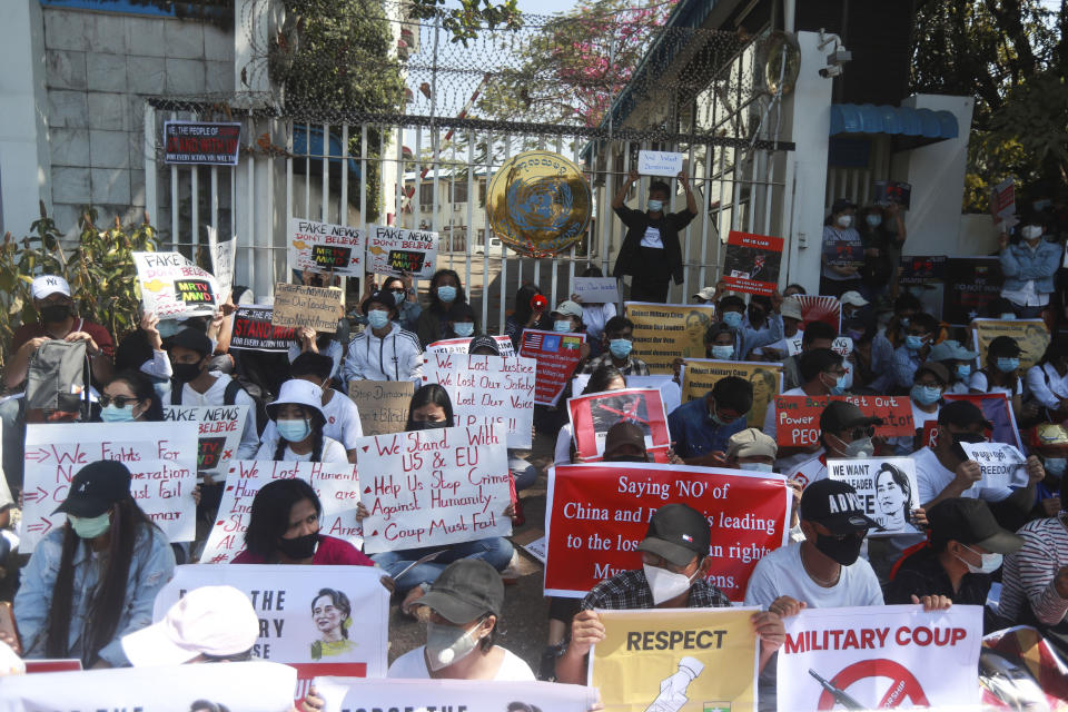 Anti-coup protesters hold posters as they gather outside the U.N. Information Office in Yangon, Myanmar, Sunday, Feb. 14, 2021. Vast numbers of people all over Myanmar have flouted orders against demonstrations to march again in protest against the military takeover that ousted the elected government of Suu Kyi. (AP Photo)