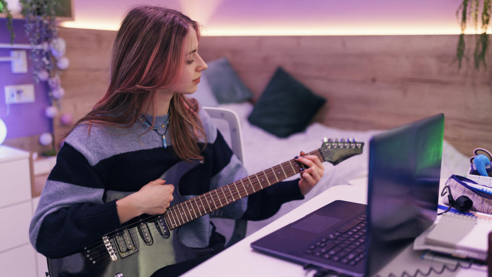 Woman playing a black electric guitar