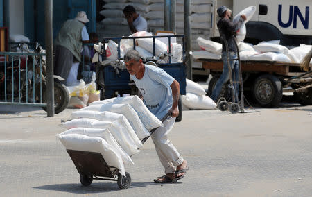 A Palestinian man pushes a cart with bags of flour at an aid distribution center run by United Nations Relief and Works Agency (UNRWA) in Khan Younis in the southern Gaza Strip September 1, 2018. REUTERS/Ibraheem Abu Mustafa
