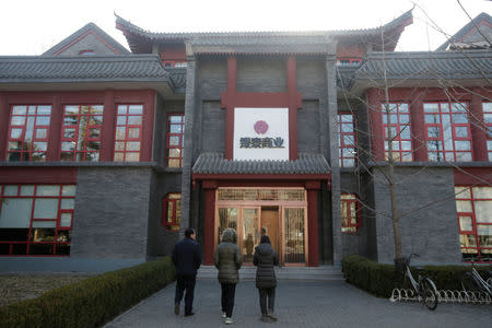 Employees walk in front of the Intime Retail Beijing office building in Beijing, China January 10, 2017. REUTERS/Jason Lee