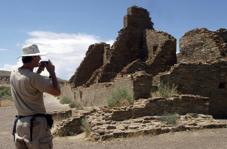 FILE - In this Aug. 10, 2005 file photo, tourist Chris Farthing from Suffolks County, England, takes a picture of Anasazi ruins in Chaco Culture National Historical Park in New Mexico. The checkerboard of federal land surrounding Chaco Culture National Historical Park would be off limits to oil and gas development under legislation pending before Congress. The U.S. House is set to vote on the measure Wednesday, Oct. 30, 2019. (AP Photo/Jeff Geissler, File)