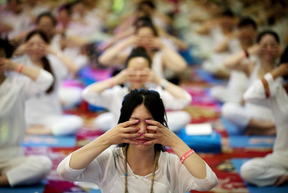 Chinese perform yoga under the instructions of Indian yoga teachers at a hotel banquet hall to mark the International Yoga Day, in Changping District, on the outskirts of Beijing, China, Sunday, June 21, 2015. Yoga enthusiasts bent and twisted their bodies in complex postures across India and much of the world on Sunday to mark the first International Yoga Day. (AP Photo/Andy Wong)