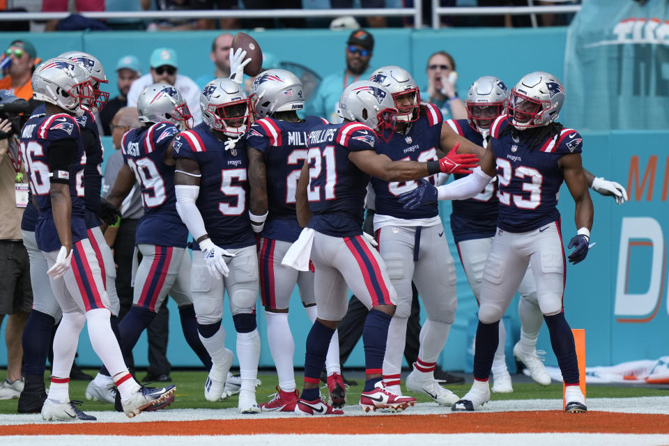 Teammates celebrate an interception by New England Patriots safety Kyle Dugger (23) during the first half of an NFL football game against the Miami Dolphins, Sunday, Oct. 29, 2023, in Miami Gardens, Fla. (AP Photo/Wilfredo Lee)