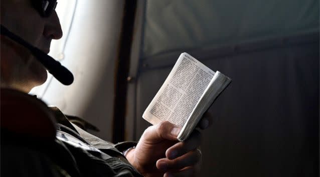 Flight Engineer Chris Poole reads a small bible aboard a Royal New Zealand Air Force (RNZAF) P3 Orion maratime search aircraft as it flies over the southern Indian Ocean looking for debris from missing Malaysian Airlines flight MH370. Photo: Getty.