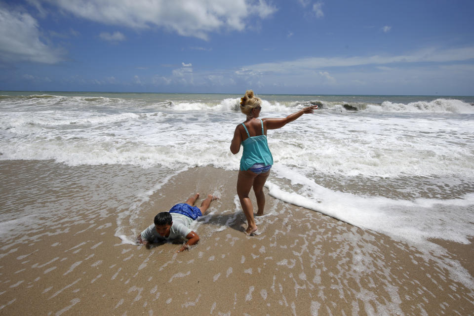 Tenille Choi and her son Remington Choi play in the high surf form the Atlantic Ocean on the barrier island in Vero Beach, Fla., Sunday, Sept. 1, 2019. The barrier island is under a voluntary evacuation today and a mandatory evacuation tomorrow in preparation for the possibility of Hurricane Dorian making landfall. (AP Photo/Gerald Herbert)