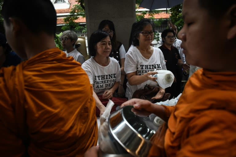 Women give alms to monks at a ceremony to commemorate the 40th anniversary of the Thammasat University student massacre in Bangkok on October 6, 2016