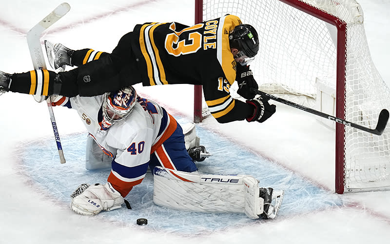 Boston Bruins center Charlie Coyle (13) goes airborne as New York Islanders goaltender Semyon Varlamov (40) makes the save in a shootout during an NHL hockey game on Dec. 13 in Boston. <em>Associated Press/Charles Krupa</em>
