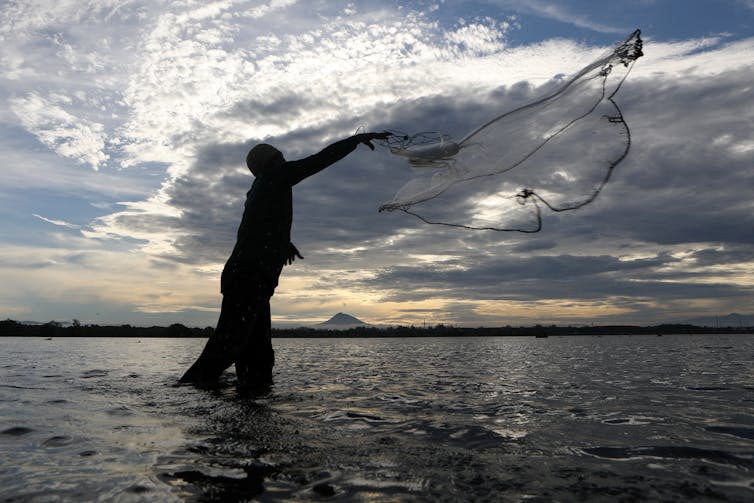 Man in silhouette casts net